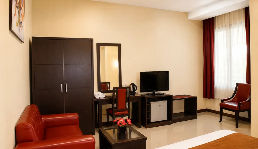 Sudut interior kamar Gumilang Hotel Puncak dengan lemari, cermin, meja, televisi, dan kursi.